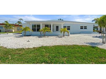 Charming single-story home featuring a white exterior, well-maintained lawn, and tropical landscaping at 6715 Georgia Ave, Bradenton, FL 34207