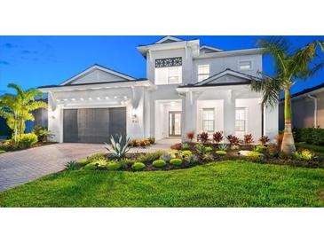 Stunning two-story home featuring a manicured lawn, lush landscaping, and a modern architectural design at 8163 Redonda Loop, Lakewood Ranch, FL 34202