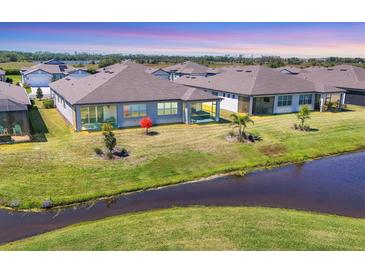 Aerial view showing a neighborhood's backyard, pond and lush green grass under a blue sky at 10519 Spring Tide Way, Parrish, FL 34219