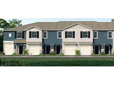 Charming townhome exterior showcasing a blue and grey facade, a one car garage, and beautifully landscaped front yard at 2469 Mellow Ln, Clearwater, FL 33765