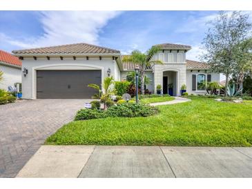 Beautiful single Gathering home with a two-car garage and meticulously landscaped yard on a sunny day at 27454 Hole In One Pl, Englewood, FL 34223
