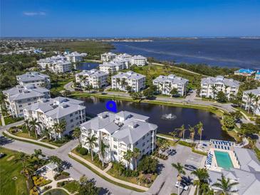 Beautiful aerial view of condo buildings with a sparkling pool, tranquil pond, and glimpses of the bay at 3420 77Th W St # 202, Bradenton, FL 34209