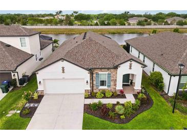 Inviting single-story home with stone accents, a well-manicured lawn, and a beautiful view of the adjacent pond at 3619 Quiet Dr, Sarasota, FL 34240