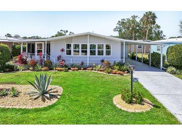 Charming single-story home featuring a lush lawn with tropical plants and a convenient covered carport at 8534 Imperial Cir, Palmetto, FL 34221
