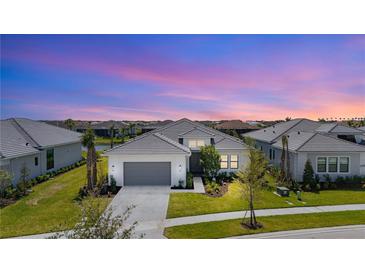 Beautiful one-story home with a gray roof, gray garage door, and tropical landscaping at sunset at 4711 Cedron Ct, Sarasota, FL 34240