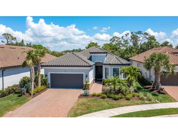 Beautiful single-story home with a tile roof, lush landscaping, a brick driveway, and an attached two-car garage at 5673 Piccolo St, Nokomis, FL 34275