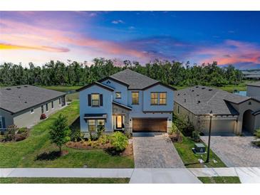 Stunning two-story home with a brick driveway, lush landscaping, and a two-car garage at 12664 Oak Hill Way, Parrish, FL 34219