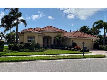 Beautiful single-story home with a red tile roof, lush landscaping, and an attached two-car garage at 193 Montelluna Dr, North Venice, FL 34275