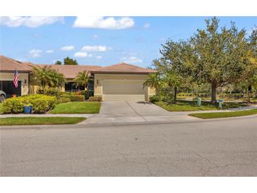 Inviting single-Gathering home featuring a tile roof, well-manicured lawn, and a two-car garage in a sunny, landscaped setting at 2064 Batello Dr, Venice, FL 34292