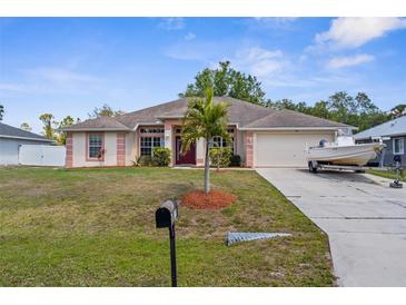 Charming single-story home with well-manicured lawn and a driveway with a boat parked on it at 2396 Malibu Ln, North Port, FL 34286
