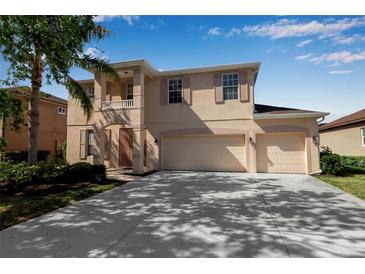 Two-story home featuring a three car garage, balcony, manicured lawn and lush landscaping at 4007 61St E Dr, Bradenton, FL 34203