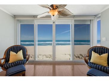 Bright sitting area showcases ocean view from two wicker chairs with striped pillows, hardwood flooring, and privacy at 5300 Gulf Dr # 204, Holmes Beach, FL 34217