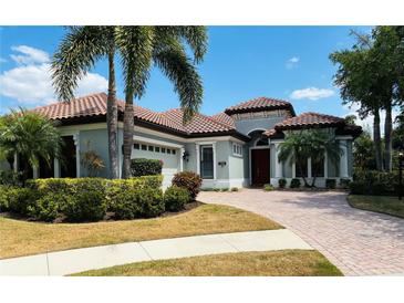 Stunning single-Gathering home with a clay tile roof, brick driveway, and lush landscaping at 7709 Hazeltine Gln, Lakewood Ranch, FL 34202