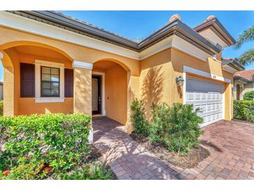 Inviting front entrance with arched doorway, shutters, and well-maintained landscaping at 10072 Cozy Grove Dr, Venice, FL 34293