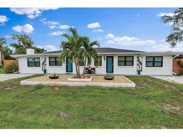 Charming home with white stucco, black trim and bright blue doors and decorative stone garden at 11 1St E St, Nokomis, FL 34275