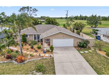 Charming home with two car garage, a pristine driveway, and manicured garden beds at 125 Golf Club Ln, Venice, FL 34293