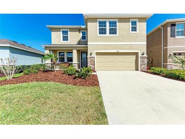 Two-story home with tan exterior, stone accents, well-maintained landscaping, and a two-car garage at 5336 Grove Mill Loop, Lakewood Ranch, FL 34211