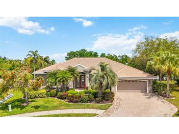 Charming home featuring a tile roof, well-manicured landscaping, and a brick-paved driveway leading to a two-car garage at 6222 Stillwater Ct, Bradenton, FL 34201