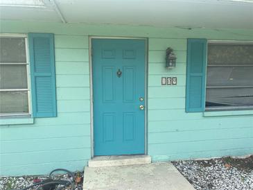 Inviting home entrance with a bright turquoise door and matching shutters on either side at 109 Colonia E Ln, Nokomis, FL 34275