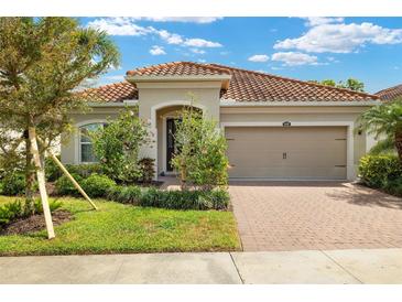 Charming single-story home with lush landscaping, brick driveway, and a beautiful terracotta tile roof at 11499 Renaissance Blvd, Venice, FL 34293