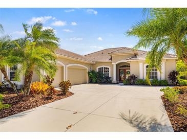 Well-maintained home with a tile roof, spacious driveway, and tropical landscaping in the front yard at 12810 Kite Dr, Bradenton, FL 34212