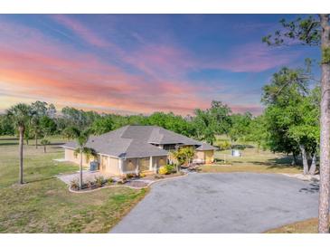 Expansive ranch home showcases lush tropical landscaping, circular drive, and a picturesque sunset backdrop at 1668 Tropicaire Blvd, North Port, FL 34286