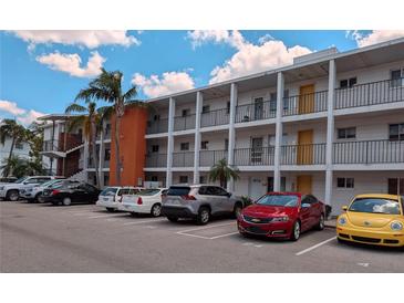 White condo building featuring orange accent with ample parking and tropical landscaping on a sunny day at 2340 Canal Dr # G-35, Bradenton, FL 34207