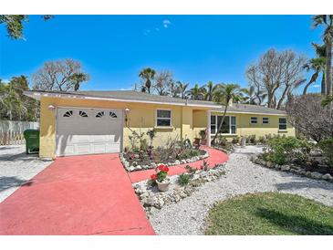 Charming yellow single-story home featuring a red driveway and well-manicured landscaping at 322 S Washington Dr, Sarasota, FL 34236