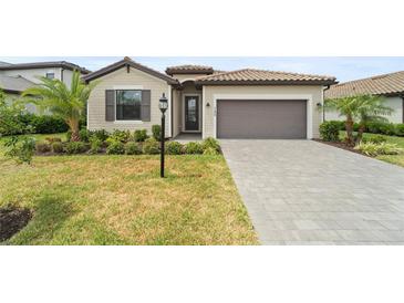 Charming single-story home with a well-manicured lawn, paver driveway, and neutral color palette at 5406 Coral Reef Way, Lakewood Ranch, FL 34211