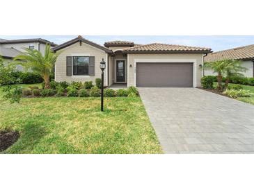 Charming single-story home with lush landscaping, a tile roof, and a paved driveway at 5406 Coral Reef Way, Lakewood Ranch, FL 34211