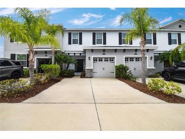 Charming townhome with a two-car garage, palm trees, and beautifully landscaped front yard at 6473 Baytown Dr, Sarasota, FL 34240