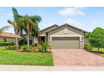 Charming single-story home with well-manicured lawn, lush landscaping, and a brick-paved driveway at 11214 Sandhill Preserve Dr, Sarasota, FL 34238
