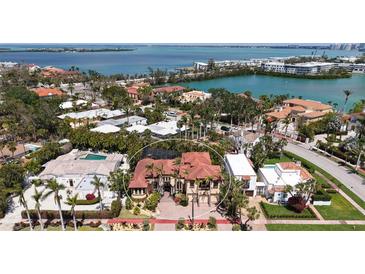 An aerial view of a luxurious waterfront home surrounded by lush tropical landscaping with a beautiful red tile roof at 113 Fillmore Dr, Sarasota, FL 34236
