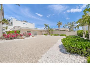 Contemporary home featuring a gravel driveway and beautiful landscaping, complemented by palm trees and vibrant bougainvillea at 1186 Center Pl, Sarasota, FL 34236