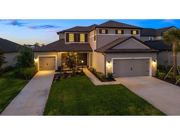 Charming two-story home featuring a manicured lawn and a three-car garage with individual doors at twilight at 16626 Paynes Mill Dr, Lakewood Ranch, FL 34211