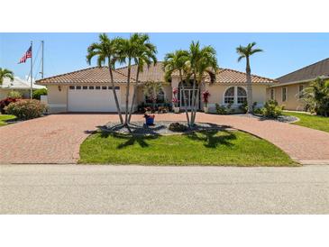 Charming home with brick driveway, palm trees, tile roof, and lush landscaping creates appealing curb appeal at 2817 La Mancha Ct, Punta Gorda, FL 33950
