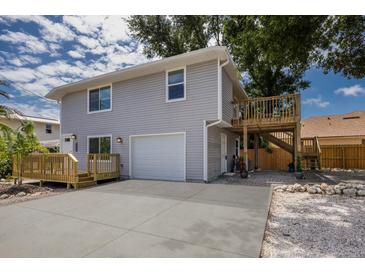Two-story home featuring a wooden deck, light gray siding, garage, and concrete driveway at 3356 Maiden Ln, Sarasota, FL 34231