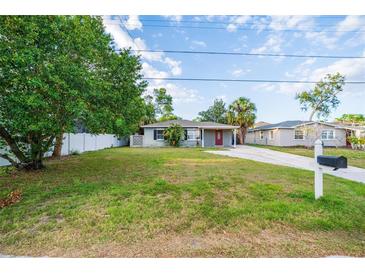 Charming single-story home features a well-manicured lawn and a classic red front door, exuding warmth at 3515 W Pearl Ave, Tampa, FL 33611