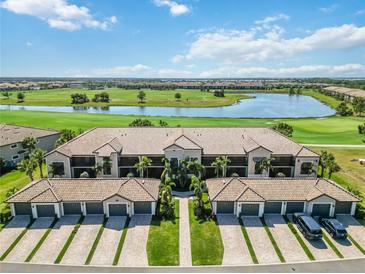 Stunning aerial view of condo building overlooking the golf course and lake with palm tree-lined entrance at 5664 Palmer Cir # 102, Bradenton, FL 34211