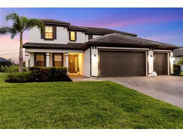 Charming two-story home with a lush green lawn and a three car garage at 11435 Apple Tree Cir, Bradenton, FL 34211