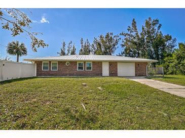 Charming single-story brick home with a well-manicured lawn and a freshly painted white metal roof at 12305 Harland St, North Port, FL 34287