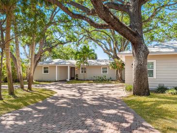 Charming single-story home with brick driveway, lush landscaping, and mature trees providing ample shade at 1248 Northport Dr, Sarasota, FL 34242