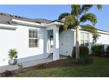 Inviting home exterior featuring a light blue facade, manicured lawn, and a lovely tropical palm tree at 17817 Woodland Ct, Punta Gorda, FL 33982