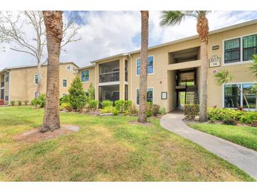 Tan condo building featuring tropical landscaping, screened patios, and well-maintained grassy areas at 4017 Crockers Lake Blvd # 1421, Sarasota, FL 34238
