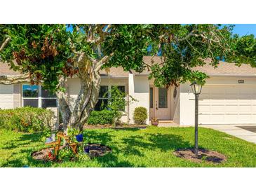 Charming home featuring a well-manicured lawn, mature tree, and inviting curb appeal at 4172 Oakhurst W Cir, Sarasota, FL 34233