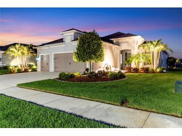 Stunning home with a well-manicured lawn and lush landscaping, illuminated by warm exterior lighting at dusk at 4625 Foxtail Dr, Parrish, FL 34219