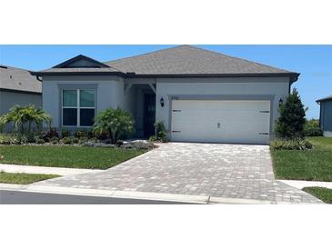 Charming single-story home featuring a brick driveway, well-manicured lawn, and a two-car garage at 8752 Coastal Key Way, Parrish, FL 34219