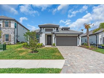 Well maintained lawn view of house with a two car garage, landscaped yard, and paver driveway at 17502 Savory Mist Cir, Bradenton, FL 34211