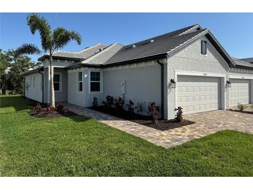 Beautifully landscaped home featuring a brick walkway, gray tile roof, and a two-car garage at 18044 Cherished Loop, Bradenton, FL 34211