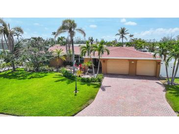 Beautiful waterfront home with lush landscaping, a paver driveway, and a spacious three-car garage at 3716 Coconut Ter, Bradenton, FL 34210